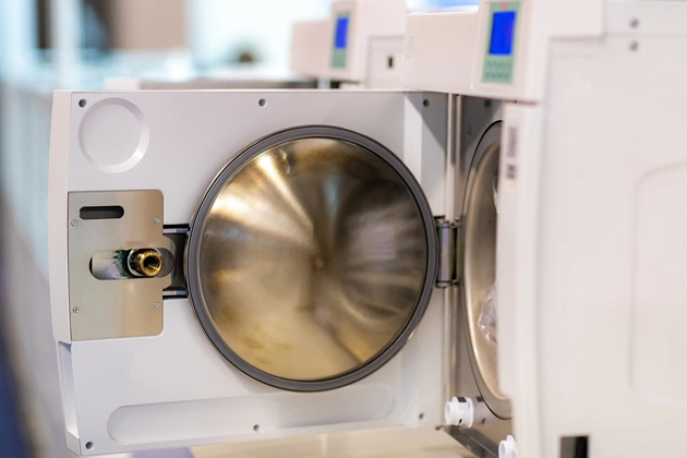Dental autoclave sterilization chamber with stainless steel door in clinical setting.