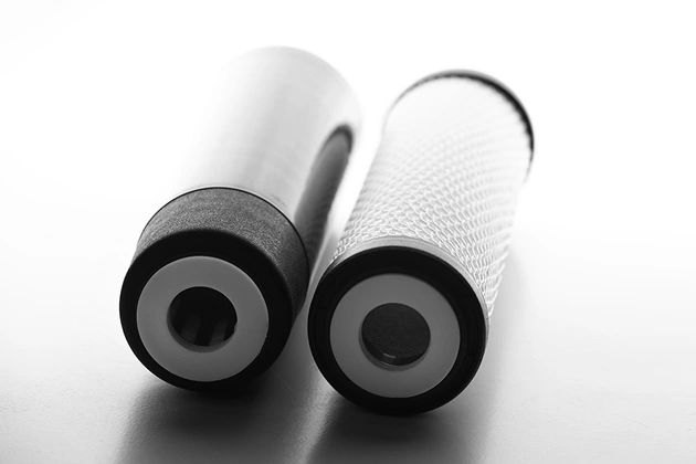 Two white cylindrical air filters with black end caps arranged side by side on reflective surface.