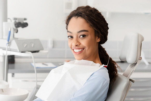 Woman smiling in dental chair wearing bib in modern dental office clinic.