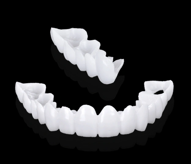 Dental veneers and crown models displayed against black background for cosmetic dentistry demonstration.
