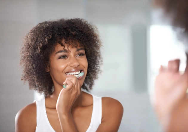 Woman brushing teeth at bathroom mirror in modern setting