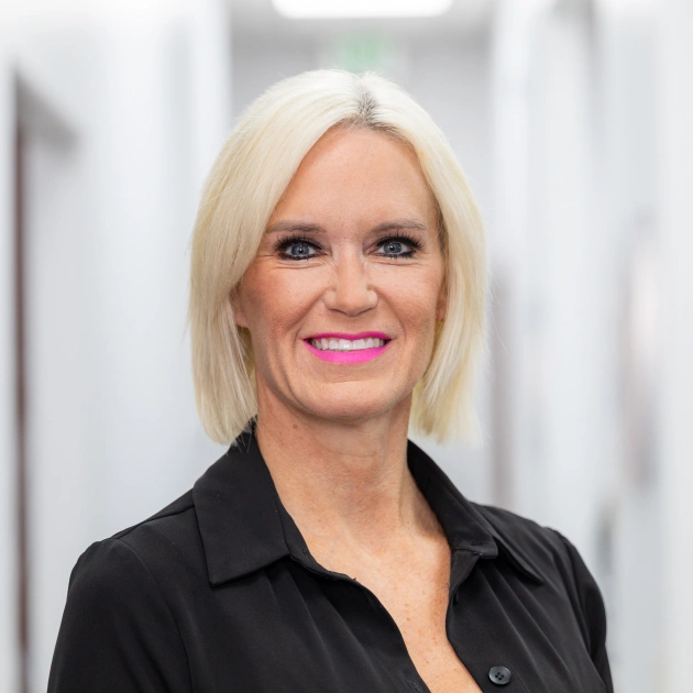 Professional woman with blonde hair wearing black shirt in dental office setting