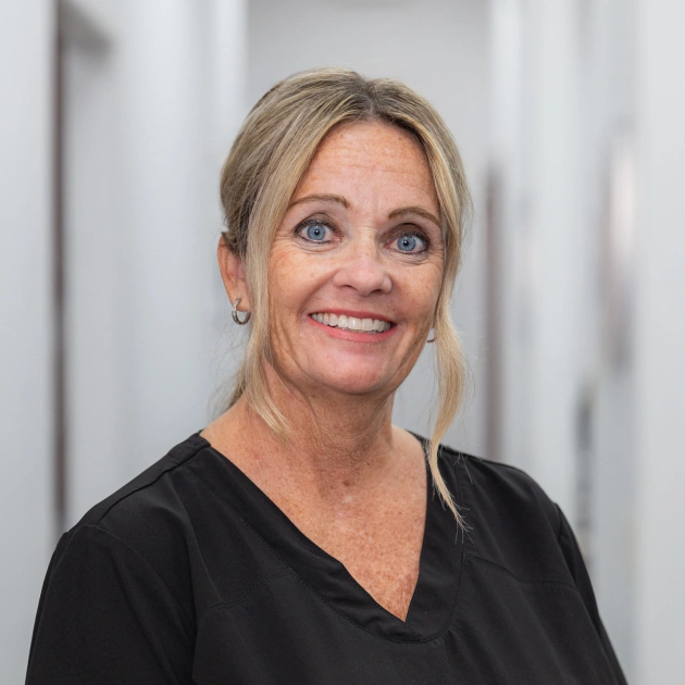 Professional dental staff member in black scrubs smiling at Island Dental clinic