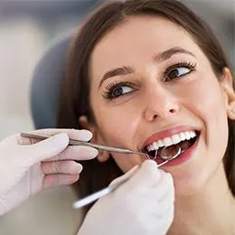 Dentist examining patient's teeth during dental checkup in clinical setting.