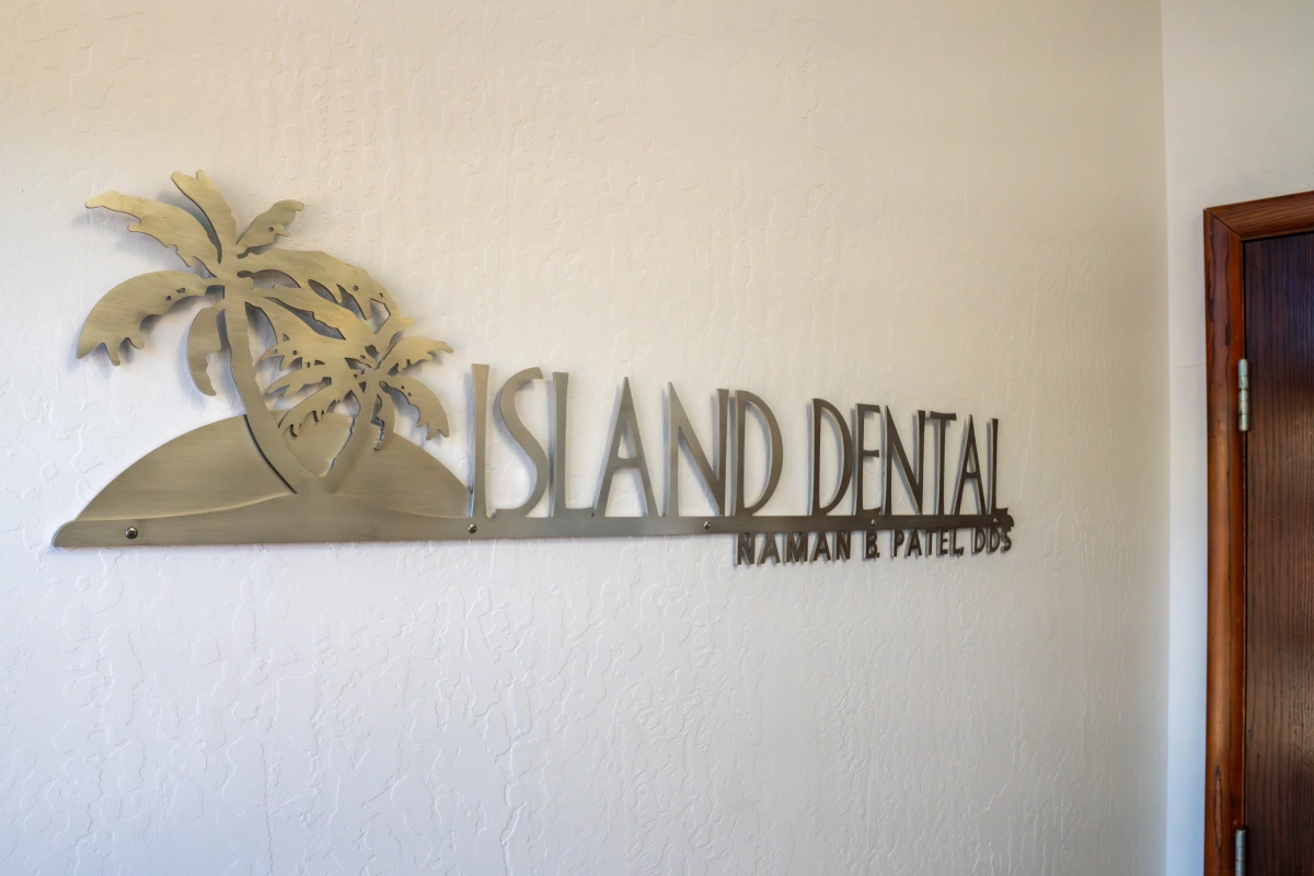 Island Dental office sign mounted on light beige wall with palm tree logo design