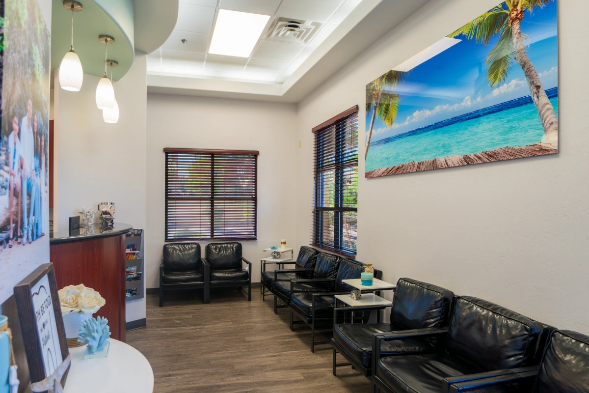 Modern dental office waiting room with beach artwork, black seating, and bright skylights