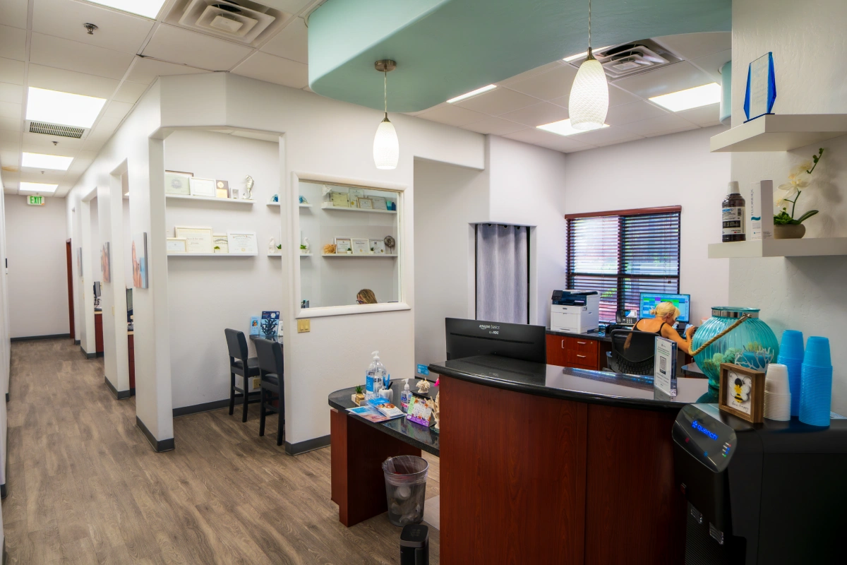 Modern dental office reception area with front desk, waiting seating, and contemporary light fixtures.