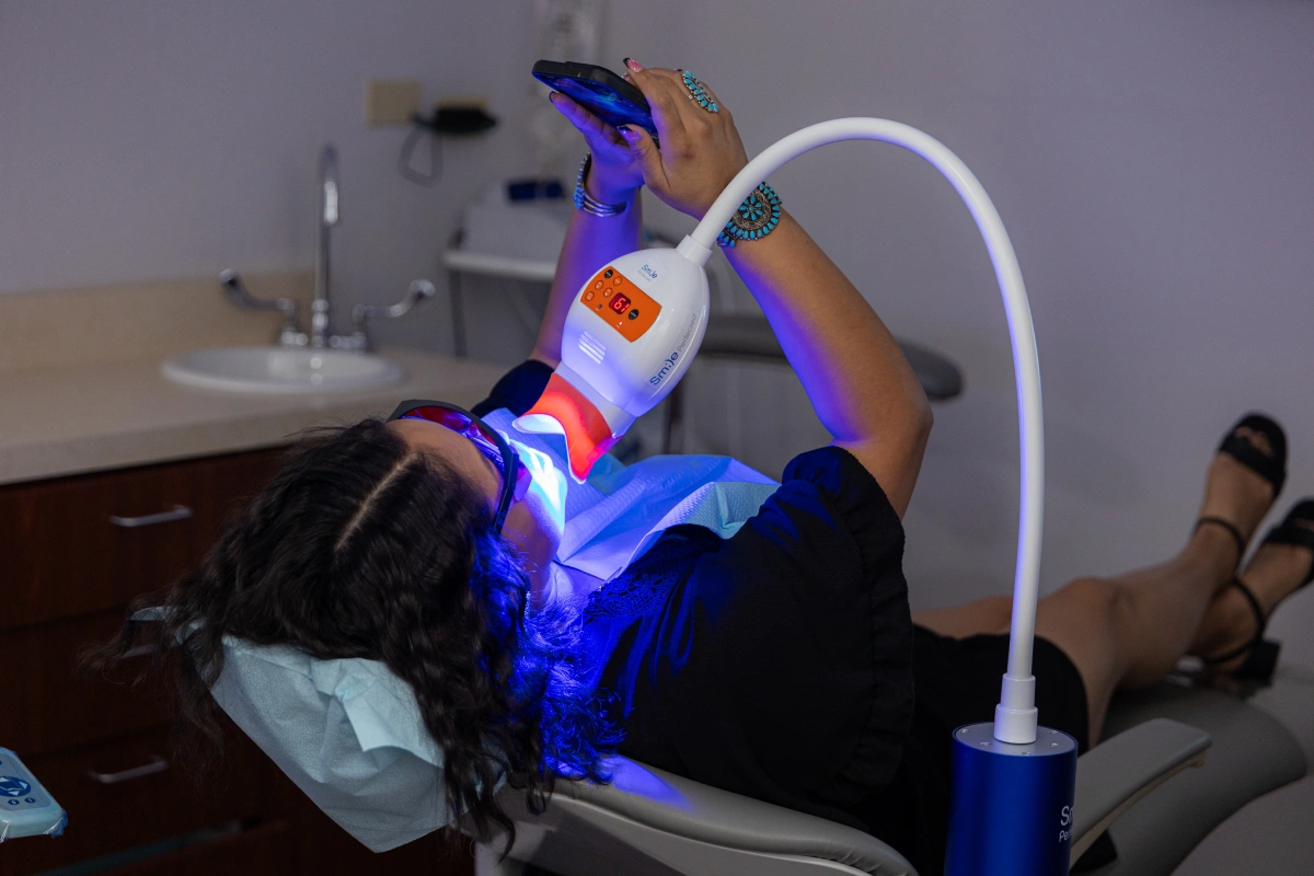 Person receiving blue LED dental whitening treatment in clinical setting
