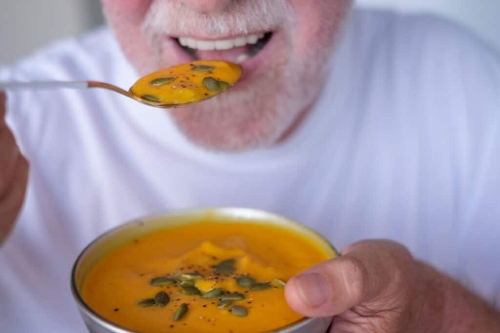 A patient enjoys a bowl of soft soup during implant surgery recovery, illustrating the importance of choosing foods that are gentle on the surgical site to support healing and reduce discomfort.