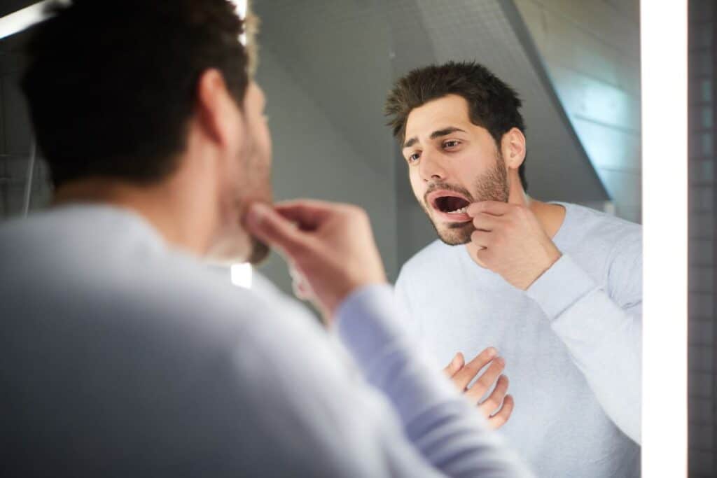 Man checking his teeth at home before visiting a Family Dentist Near Me in Gilbert, AZ