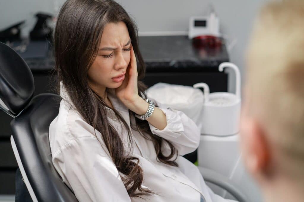 A patient experiencing jaw pain during a dental consultation before receiving TMJ treatment.